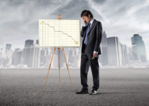 Sad businessman standing in front of stock chart